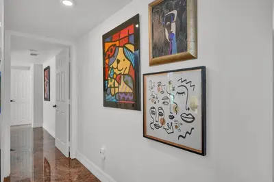 a hallway with four paintings on the wall at Treetop Retreat! Cozy 2 Bedroom In Heart Of Grove in Miami