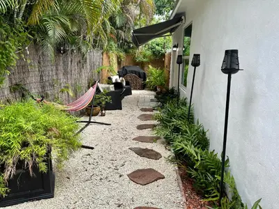 a garden with a patio with a couch and a fence at Flora's Garden Apartment/Studio in North Miami