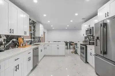 a large kitchen with white cabinets and stainless steel appliances at VillaKoBo Heated Pool Spa Bar Tennis Golf in Miami