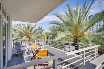 a balcony with chairs and a table and palm trees at Miami Beach Vacation Rental with Rooftop Pool Access in Miami Beach