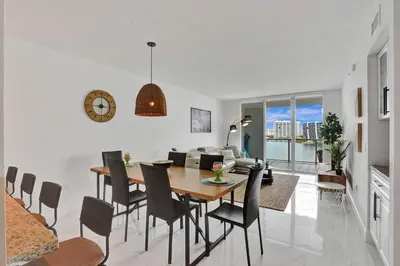 a dining room and living room with a table and chairs at Marina Bay Sunny Isles 1005 in Miami Beach