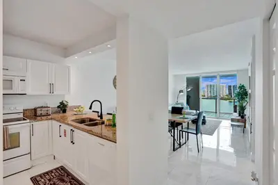 a kitchen with white cabinets and a dining room at Marina Bay Sunny Isles 1005 in Miami Beach