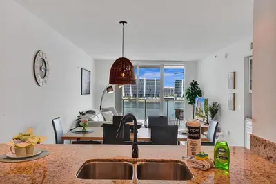 a kitchen with a sink and a living room at Marina Bay Sunny Isles 1005 in Miami Beach