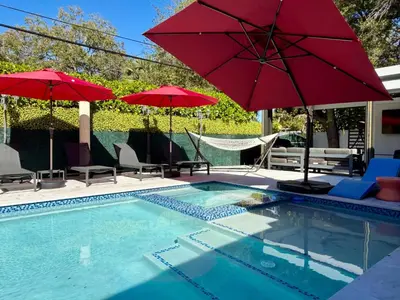 a swimming pool with red umbrellas and chairs and a pool at VillaLee Luxury Heated Pool & Spa Sauna Golf in North Miami