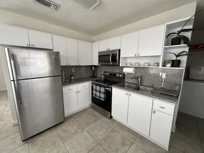 a kitchen with white cabinets and a stainless steel refrigerator at Miami's Cozy Tropical Getaway in Miami