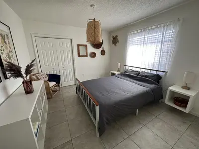 a bedroom with a bed and a chair and a window at Miami's Cozy Tropical Getaway in Miami