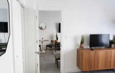 a living room with a flat screen tv on a wooden cabinet at Newely remodeled apartment only 1 min to the beach! in Miami Beach