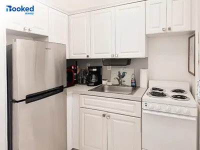 a kitchen with white cabinets and a white refrigerator at Steps to the beach! in Miami Beach