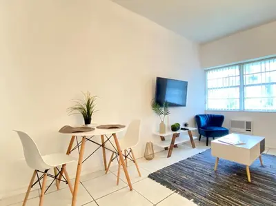 a living room with a table and chairs and a tv at MIAMI BEACH HOME NEAR THE OCEAN in Miami Beach
