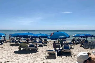 a group of people sitting on a beach with umbrellas at Ocean Breeze & City Style, Miami Beach Luxury Stay -A in Hallandale Beach