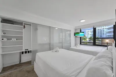 a white bedroom with two beds and a window at Modern Miami Beach Condo with Beach Service & Pool in Miami Beach