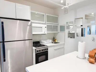 a kitchen with white cabinets and a stainless steel refrigerator at 2 BEDROOM ON THE BEACH ! in Miami Beach