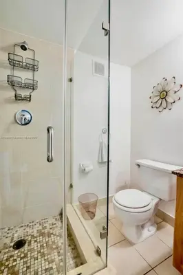 a bathroom with a toilet and a glass shower at Amazing condo 5 minute walk to the beach! in Miami Beach