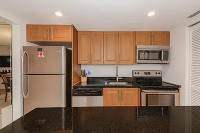 a kitchen with stainless steel appliances and wooden cabinets at Amazing condo 5 minute walk to the beach! in Miami Beach