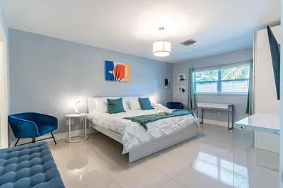 a bedroom with a bed and a blue chair at Villa Aura Heated Pool 4 Bedrooms 5 minutes to the Ocean in Fort Lauderdale
