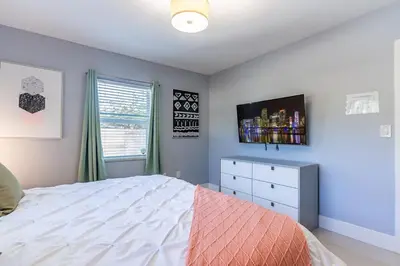 a bedroom with a bed and a dresser with a tv at Villa Aura Heated Pool 4 Bedrooms 5 minutes to the Ocean in Fort Lauderdale