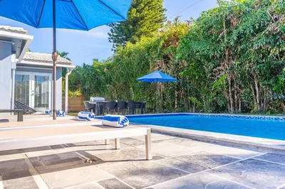 a pool with a table and an umbrella next to a pool at Villa Aura Heated Pool 4 Bedrooms 5 minutes to the Ocean in Fort Lauderdale