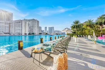 a pool at a hotel with chairs and a table at Pool Apartment with Balcony Near Beach in Hallandale Beach