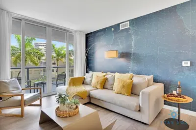 a living room with a white couch and a blue wall at Pool Apartment with Balcony Near Beach in Hallandale Beach