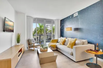 a living room with a white couch and a blue wall at Pool Apartment with Balcony Near Beach in Hallandale Beach