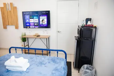 a room with a bed and a tv and a refrigerator at Insta Worthy Oasis in Homestead