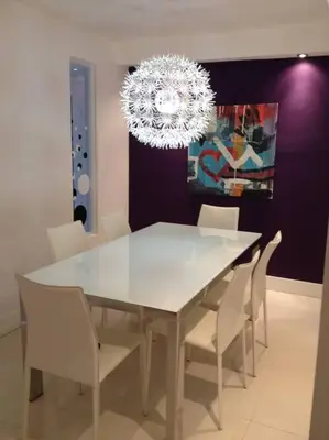 a dining room table with white chairs and a chandelier at Apartamento en Miami Beach sobre la playa in Miami Beach