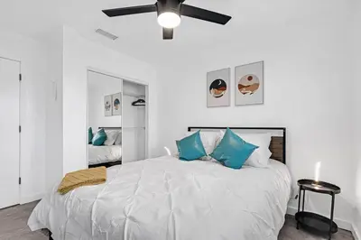 a bedroom with a bed with blue pillows and a ceiling fan at Spacious 5 Bedrooms with Large Pool, 12 minutes to the Ocean in Fort Lauderdale