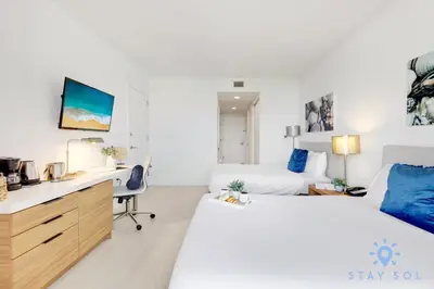 a bedroom with two beds and a desk and a desk at Balcony - Pool - Near Beach - Gym in Hallandale Beach