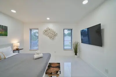 a white bedroom with a large bed and a flat screen tv at Top Location Villa at Highland Lakes Blvd BY THE GLAMHOMES in Miami