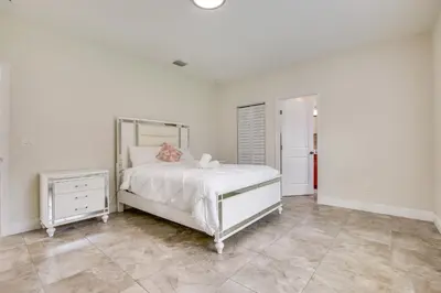 a white bedroom with a bed and a mirror at Stylish Fort Lauderdale Home 5 Mi to Beach! in Fort Lauderdale