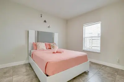 a bedroom with a bed with pink sheets and a mirror at Stylish Fort Lauderdale Home 5 Mi to Beach! in Fort Lauderdale