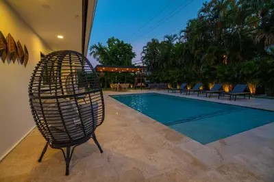 a wicker chair sitting next to a swimming pool at Amazing Villa at Highland Lakes Boulevard BY THE GLAMHOMES in Miami