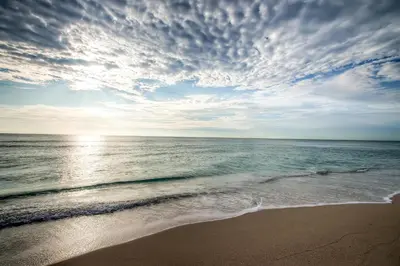 a beach with a cloudy sky and the ocean at Churchill Suites Monte Carlo Miami Beach in Miami Beach