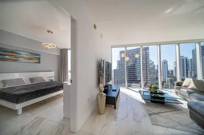 a bedroom with a bed and a living room with a large window at Luxury Ocean View 2BR Corner Unit at W residence in Miami