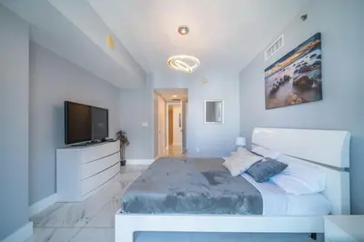 a bedroom with a large bed and a flat screen tv at Luxury Ocean View 2BR Corner Unit at W residence in Miami