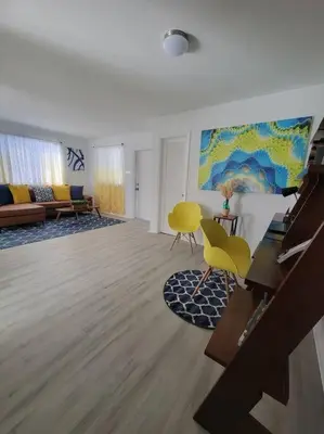 a living room with yellow chairs and a painting on the wall at Sol Miami # 2 with free parking in Miami