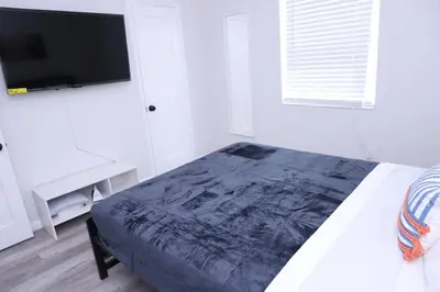 a white bedroom with a bed and a tv at Douglas rd apartments in Miami