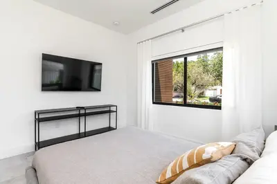 a white bedroom with a couch and a tv on the wall at Super Modern Waterfront Paradise Near the Beach in Miami
