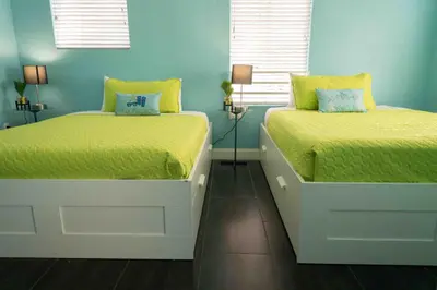 two beds in a bedroom with blue walls at Beds n' Drinks in Miami Beach