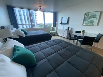 a bedroom with two beds and a desk and a table at Studio Miami Beach sobre la playa in Miami Beach