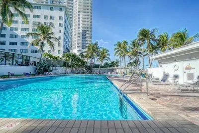 a swimming pool with palm trees and buildings at Deluxe Studios and Apartments at the Casablanca in Miami Beach