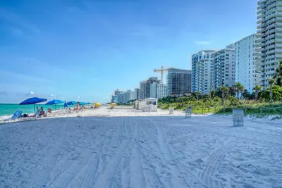 a sandy beach with some buildings and the ocean at Deluxe Studios and Apartments at the Casablanca in Miami Beach