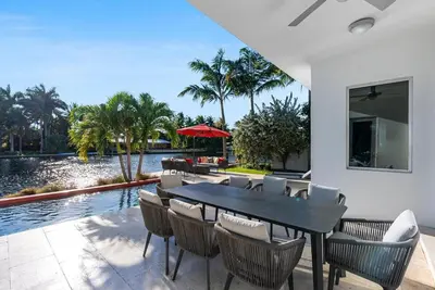 a dining room with a table and chairs next to a pool at VILLA ST-BARTH Waterfront w htd pool by VIAC in Fort Lauderdale