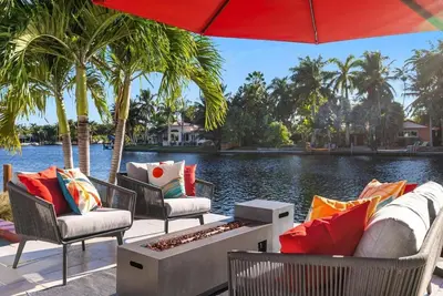 a group of chairs and an umbrella next to a body of water at VILLA ST-BARTH Waterfront w htd pool by VIAC in Fort Lauderdale