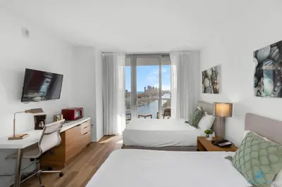 a hotel room with two beds and a desk and a window at Infinite View - Balcony - Pool - Gym - Near Beach in Hallandale Beach
