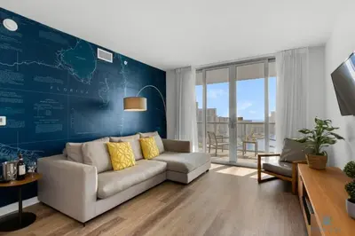 a living room with a couch and a blue wall at Infinite View - Balcony - Pool - Gym - Near Beach in Hallandale Beach