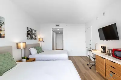 a hotel room with two beds and a flat screen tv at Infinity View - Balcony - Pool - Gym - Near Beach in Hallandale Beach