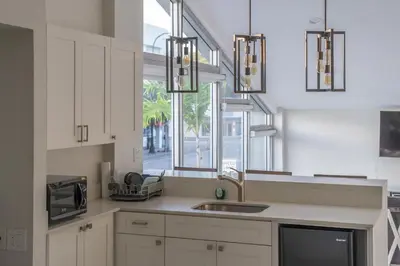 a kitchen with white cabinets and a sink and a window at The Biscayne Hotel in Miami