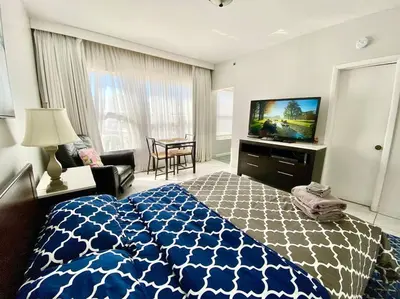 a bedroom with a blue and white bed and a television at APARTMENT RIGHT ON THE BEACH! in Miami Beach