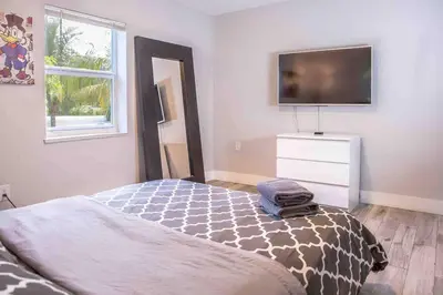 a bedroom with a bed and a tv on the wall at HOUSE WITH POOL, 10 MINS DRIVE TO THE BEACH! in Miami Shores